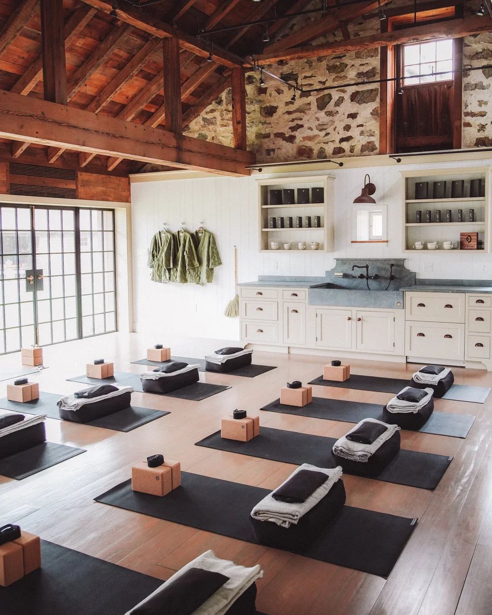 A movement studio with mats laid out under a timber-beamed ceiling