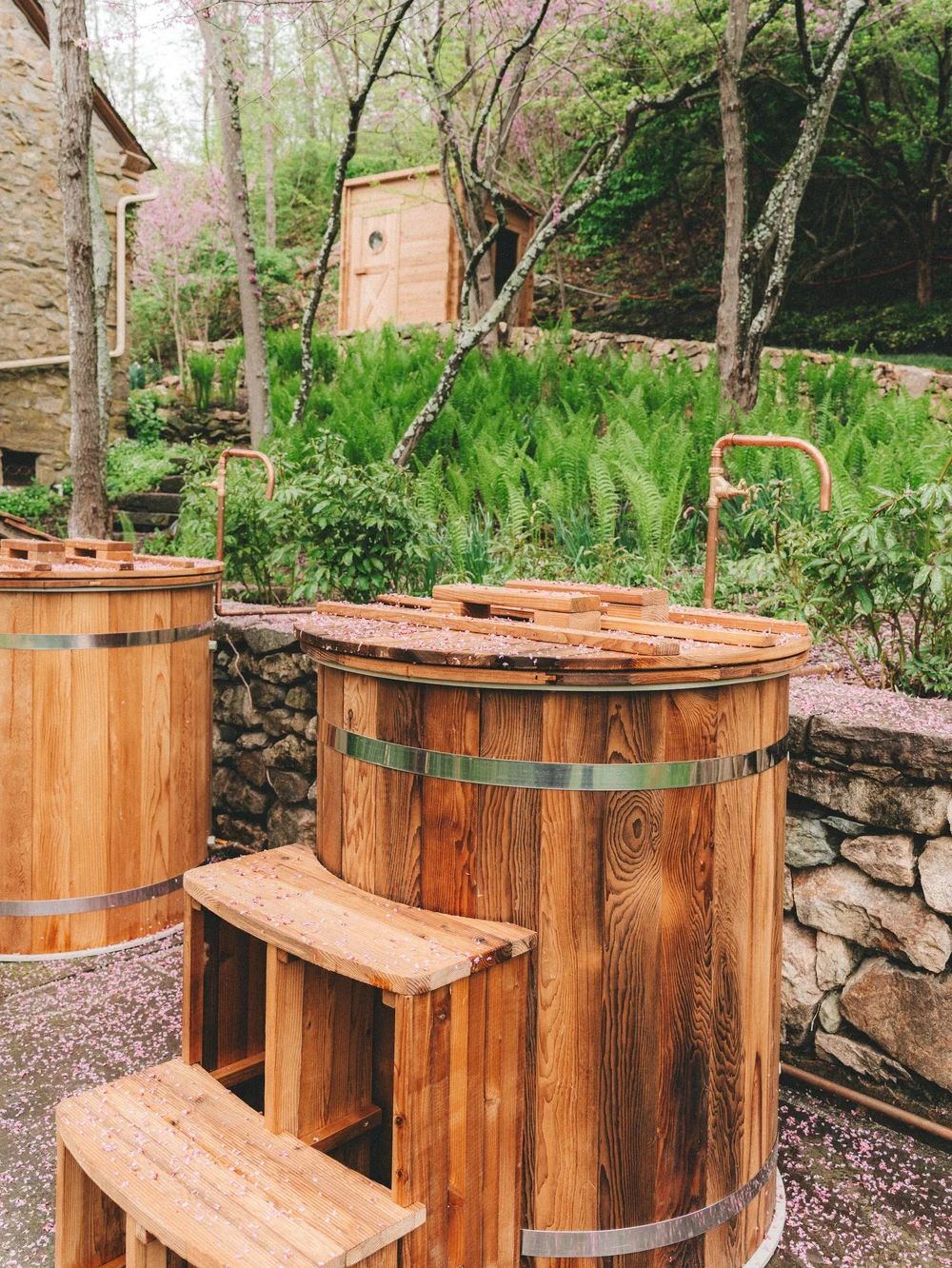 Cedar cold-plunge barrels on a stone terrace at the edge of the woods