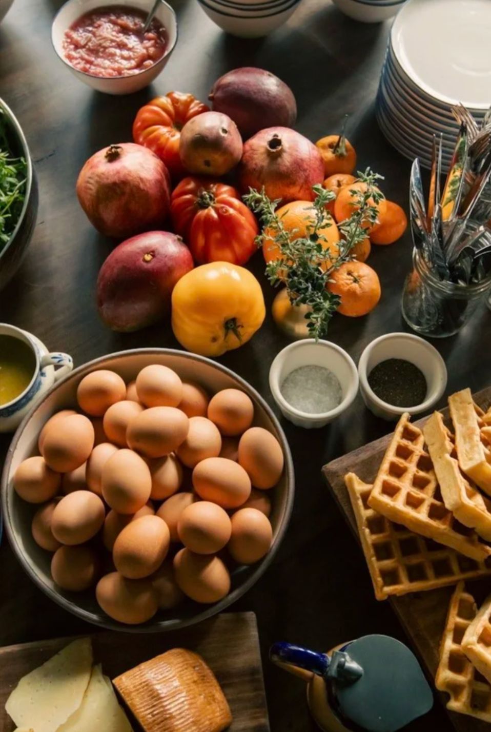 A spread of fresh fruit, eggs and waffles laid out for breakfast