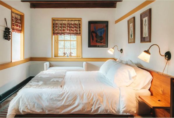 A bedroom with two white-linen beds against a wooden headboard