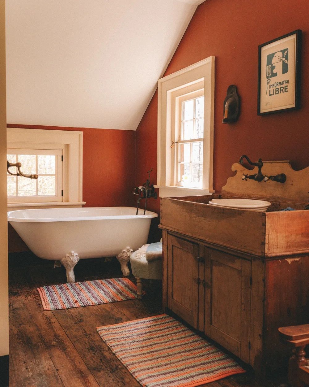 A bathroom with a clawfoot tub and deep rust-red walls
