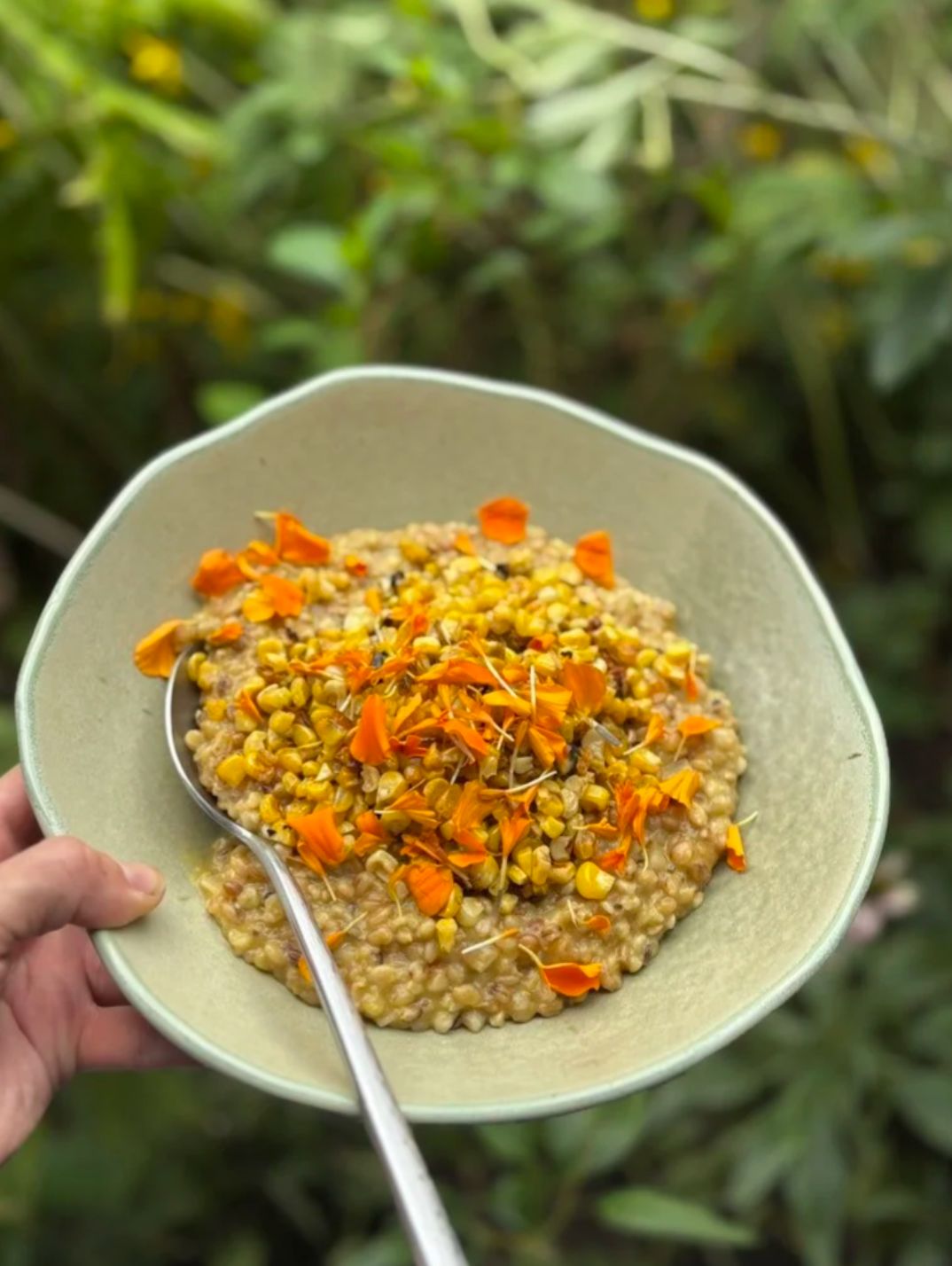 A bowl of grain salad scattered with edible flowers
