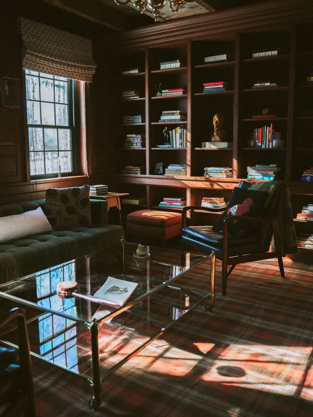 A library of full bookshelves and leather armchairs in afternoon light