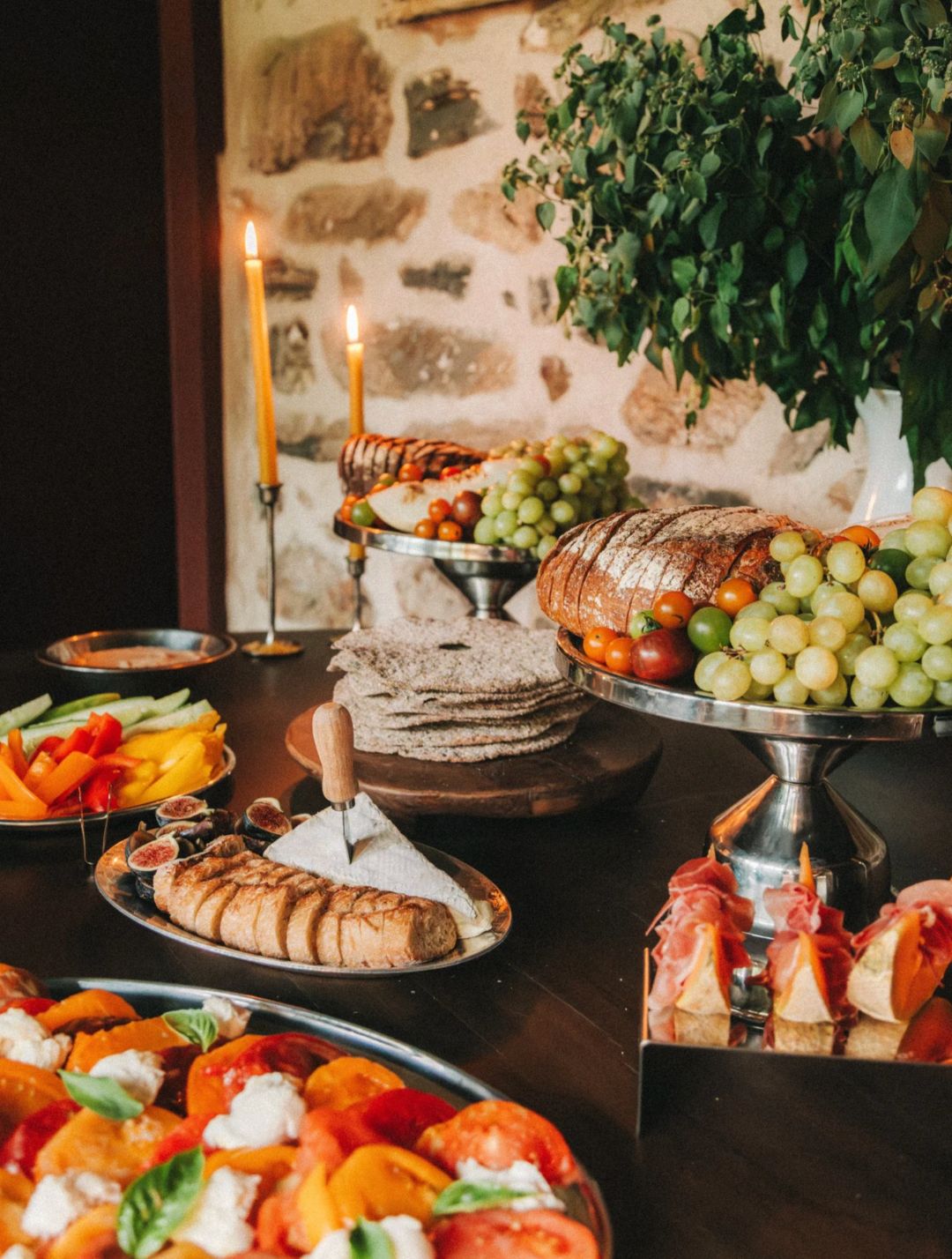 A candlelit table laid with pastries, fruit and bread