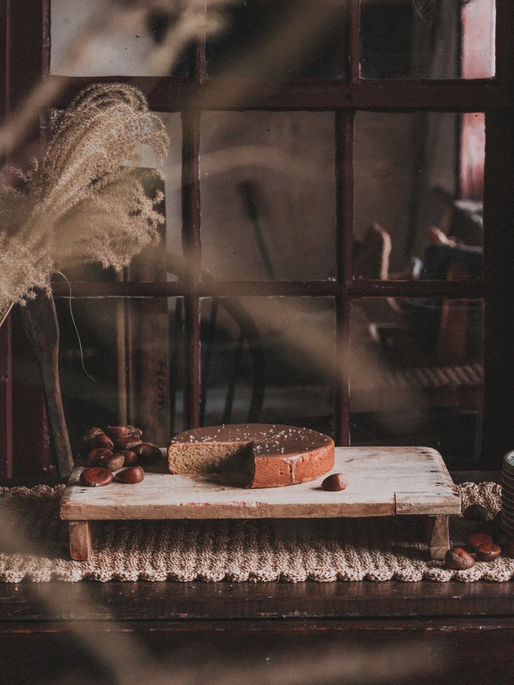 A loaf of bread resting on a wooden board by a window