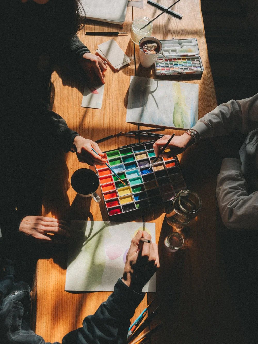 Hands painting with watercolours at a table